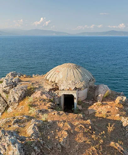 A historic military bunker on Sazan Island, Albania, overlooking the deep blue waters of the Adriatic Sea.