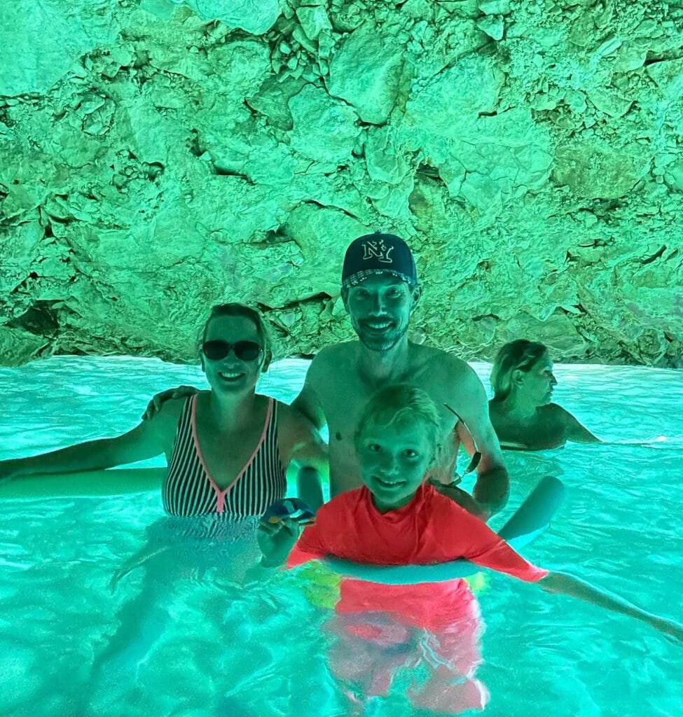 A family, inside the hidden blue cave,surrounded by luminous turquoise waters and dramatic limestone formations. in Vlore, Albania